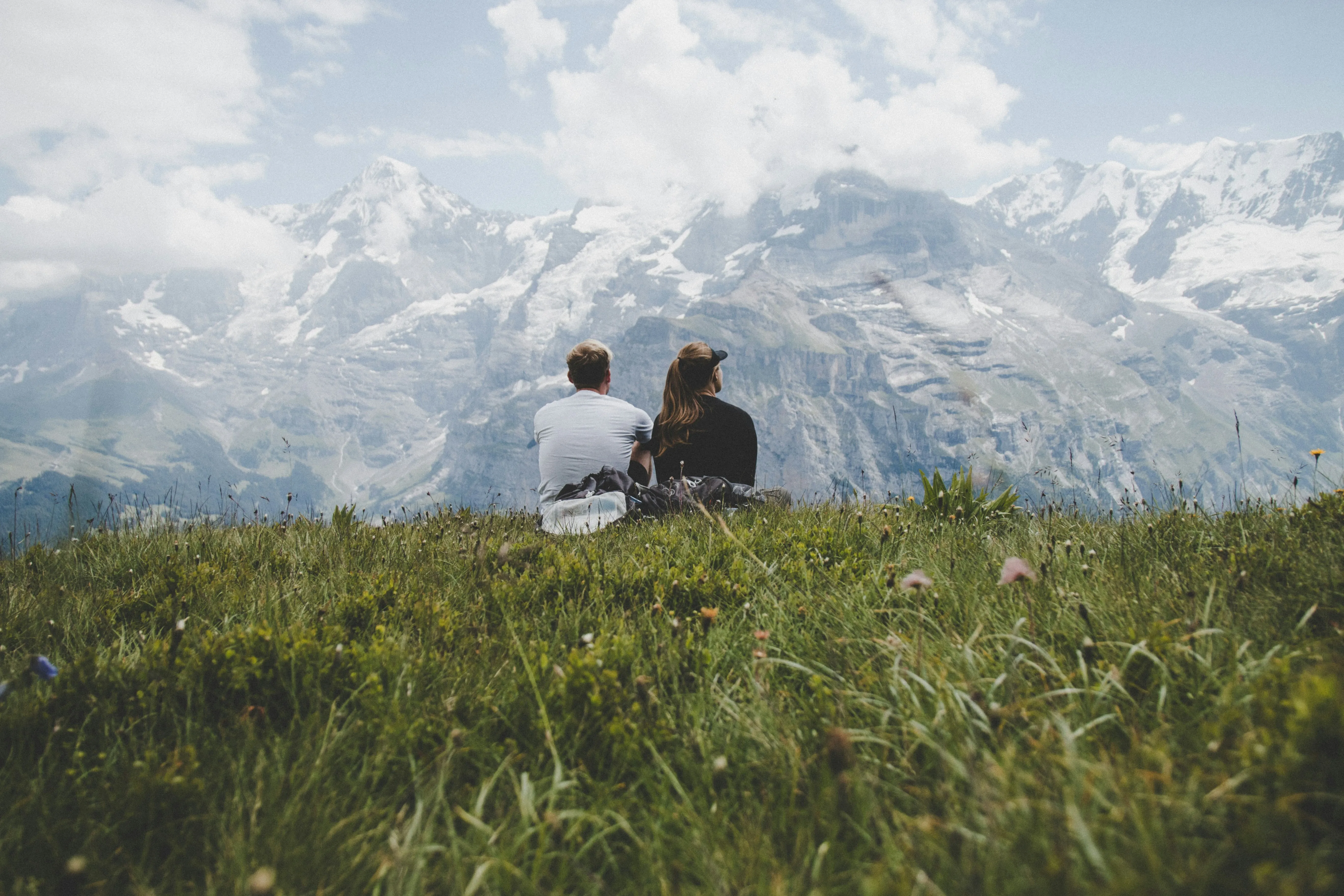 Young couple standing in a grassy field with mountains in the background